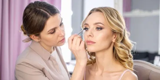 Professional makeup artist applying eye makeup to a woman during a beauty consultation at a makeup studio