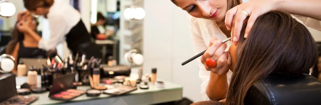 Professional makeup artist applying eye makeup to a client in a beauty salon using cosmetic brushes and products
